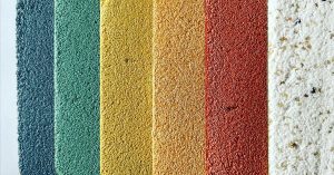 Colorful textured plaster wall finish samples in blue, green, yellow, orange, red, and white, arranged vertically on a neutral background