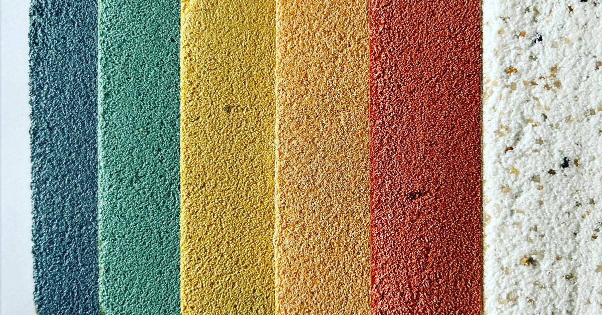Colorful textured plaster wall finish samples in blue, green, yellow, orange, red, and white, arranged vertically on a neutral background
