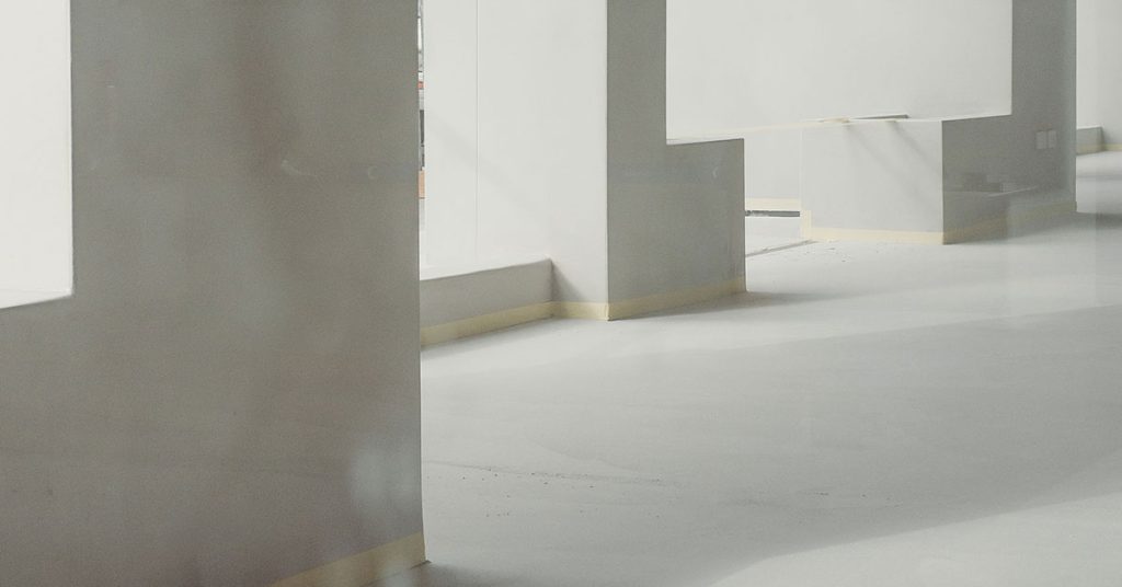 Modern interior showcasing microtopping pros and cons through Terrazzo GraniTech seamless flooring - smooth gray surfaces with integrated steps and columns demonstrating the superior durability, aesthetic appeal, and jointless finish that addresses traditional microtopping limitations with advanced resin-based technology
