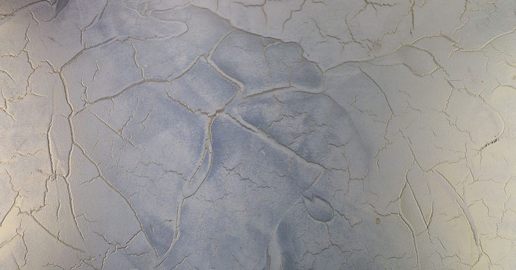 Severe microcement cracking showing extensive network of fissures and blue staining damage across surface, demonstrating why microcement crack easily without proper application