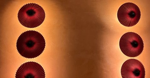 Glatte orangefarbene Putzwand mit dekorativen kreisförmigen Elementen, die eine rissfreie Oberfläche zeigt und Putzrisse an Wänden verhindert