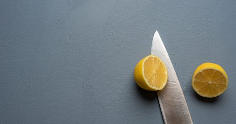 Nahaufnahme von blauem Küchenwandputz mit texturierter Oberfläche, Messer und Zitronenscheiben; demonstriert das lebensmittelechte Wandputz-Finish und die Haltbarkeit der Küchenputz-Applikation für kulinarische Räume