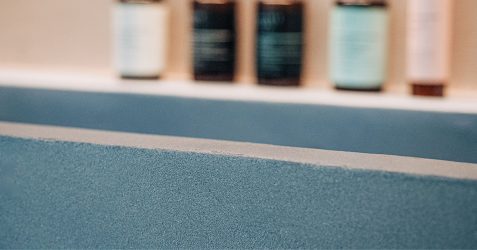 Vorgestelltes Bild, das eine blaue Terrazzo-Microtopping-Arbeitsplattenoberfläche mit nahtloser Oberfläche und Granit-Aggregat-Textur zeigt, die moderne dekorative Betonbeschichtungsoptionen für den Microtopping- vs. Mikrozement-Vergleichsleitfaden darstellt.