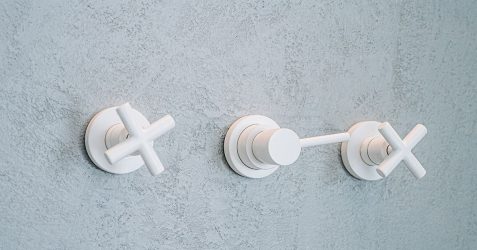 Waterproof wall plaster surface in Terrazzo GraniTech finish with textured gray appearance, featuring three modern white bathroom fixtures mounted on the wall