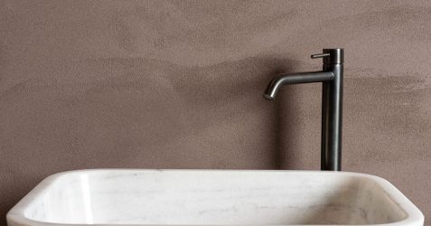 Modern bathroom with subtle textured wall finish in neutral taupe color featuring contemporary black faucet and white marble sink